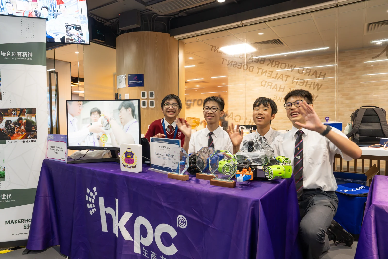 Four smiling students showcasing their underwater robot and awards at a MakerHolic exhibit